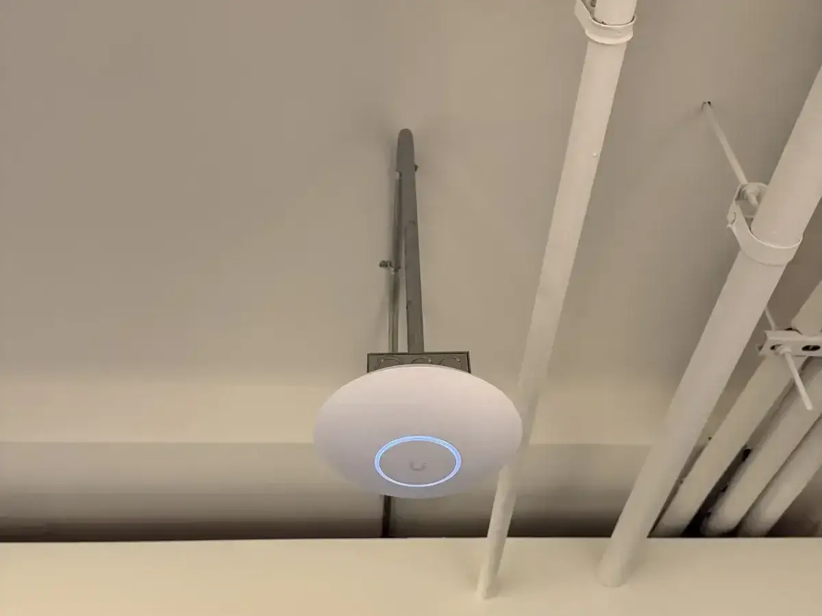 Wireless Networks in NYC, NJ & CT 8 UniFi Wi-Fi 7 access point above a glass office entrance at Cogency Global, installed by Solved IT