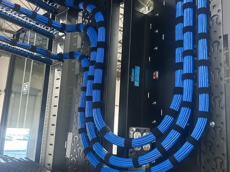 Neatly dressed blue Cat 6a cabling in a wall-mounted network cabinet at Lindenmeyr Munroe, installed by Solved IT