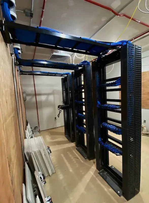 New network room at a Phipps property: overhead cable trays and racks with dressed blue cabling, installed by Solved IT